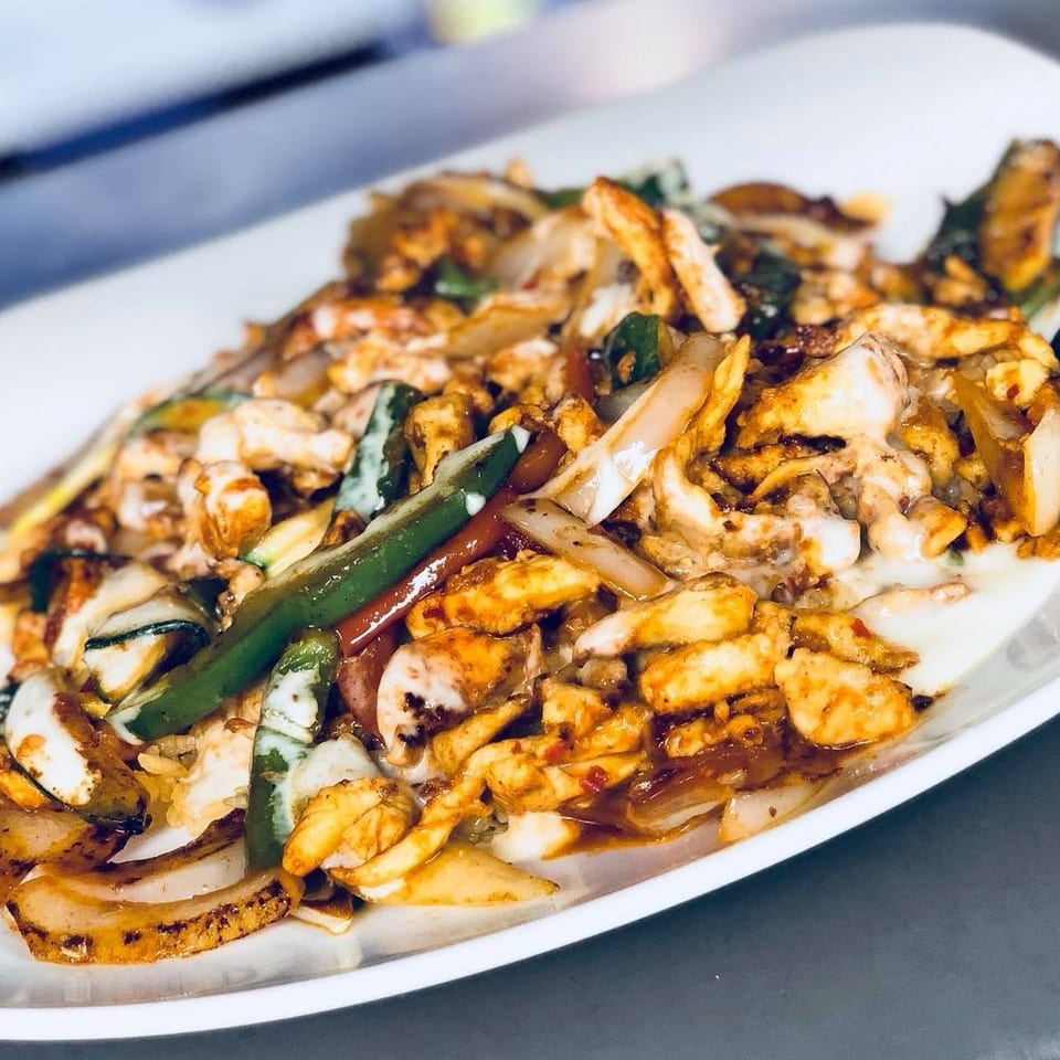 Chicken fajitas with grilled onions, green peppers, and zucchini on a white plate.