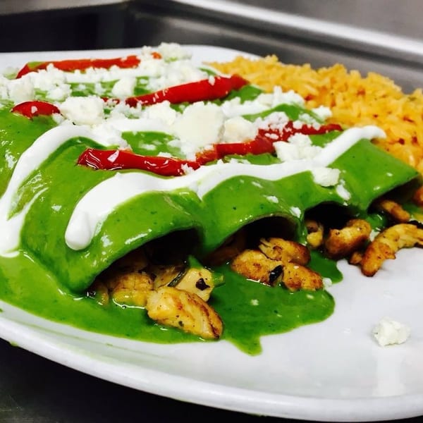 Three green enchiladas topped with crema, cotija cheese, and red peppers, served with rice.