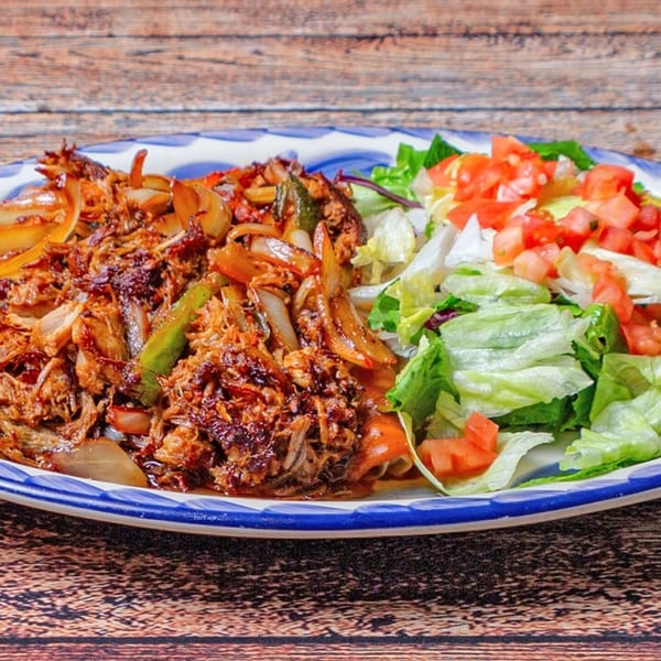 Shredded beef fajitas with sautéed onions and peppers, alongside a fresh green salad with diced tomatoes.